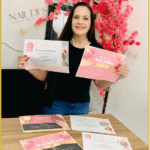 Aluna do curso Nail Designer 4.0 segurando certificados de conclusão