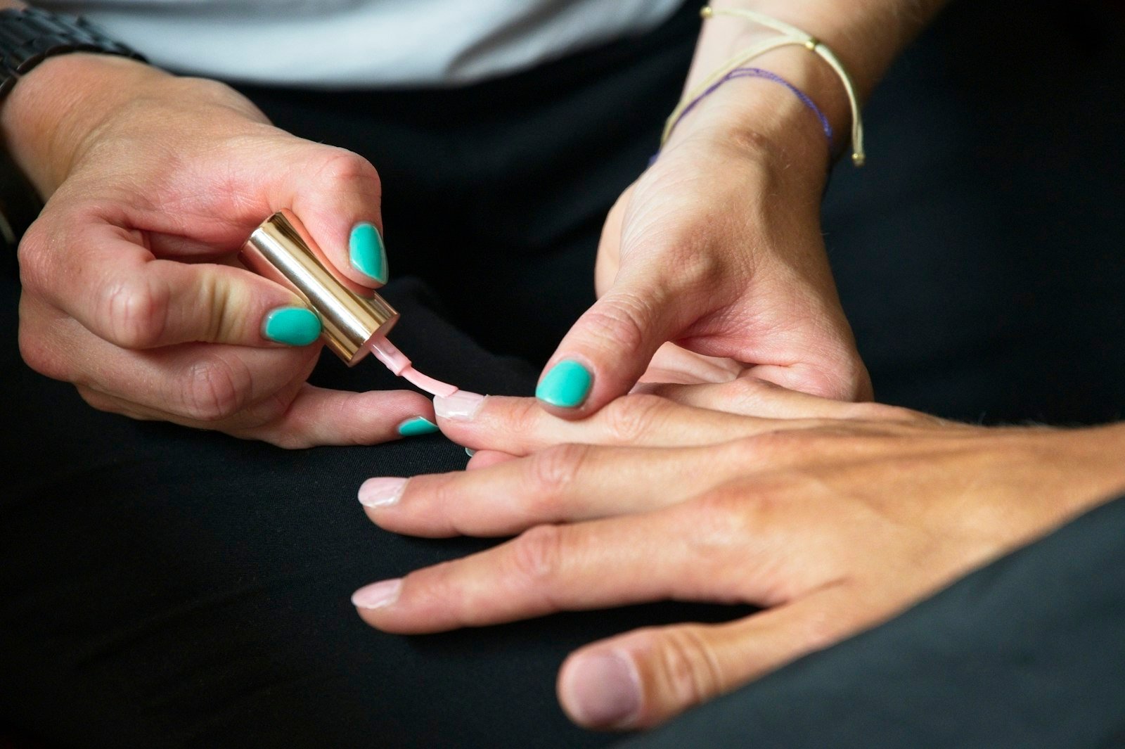Mãos de cliente com unhas coloridas sendo preparadas em um atendimento de manicure