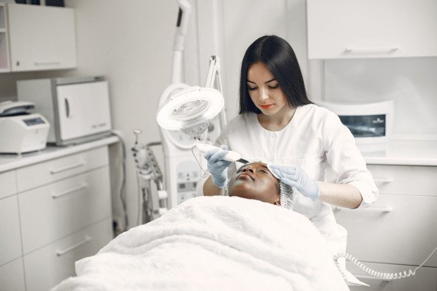 Esteticista aplicando procedimento de limpeza de pele facial
