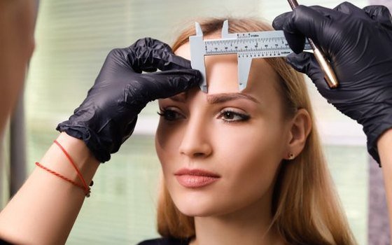 Esteticista medindo sobrancelha com paquímetro para mapeamento facial