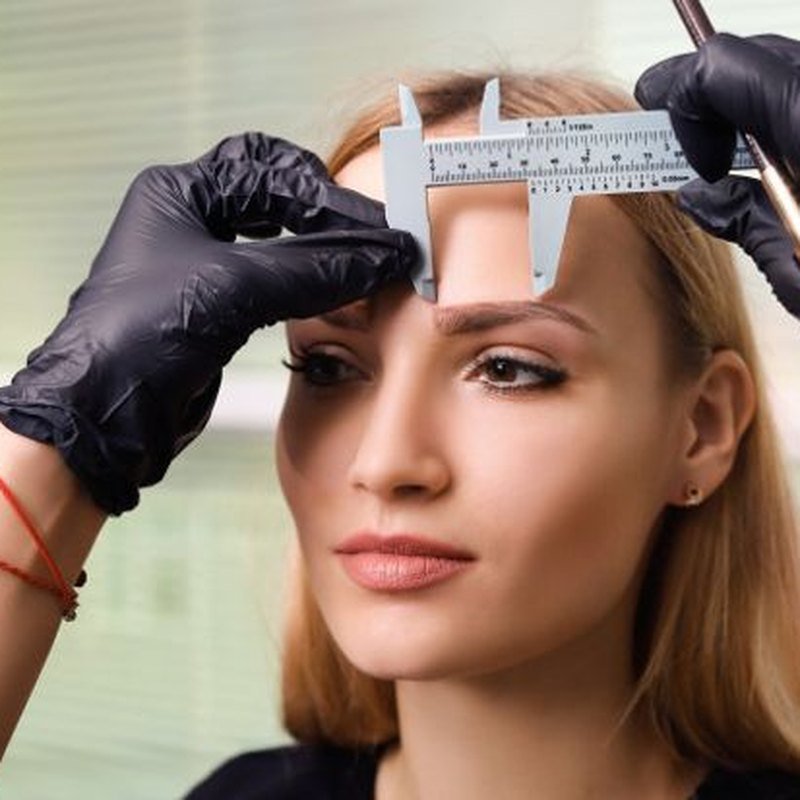Esteticista medindo sobrancelha com paquimetro para mapeamento facial