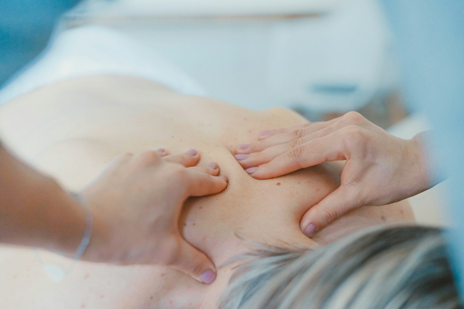 Profissional de estética fazendo massagem corporal nas costas de uma cliente na maca