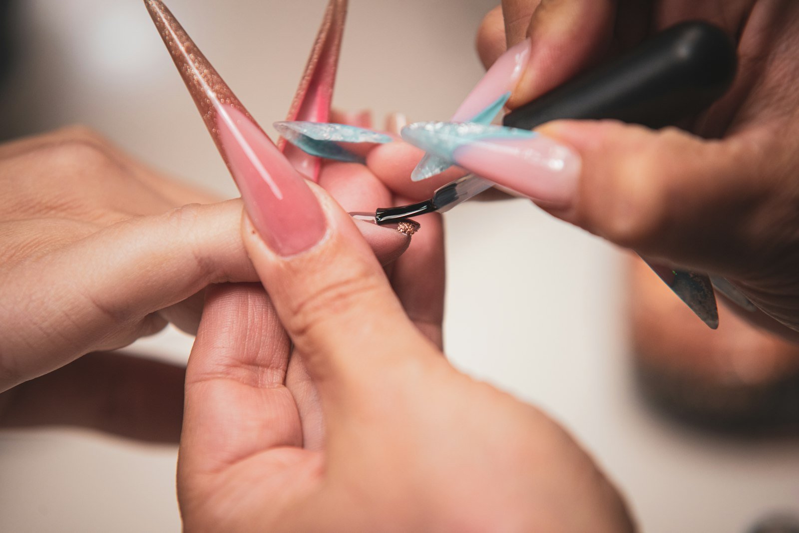 Manicure profissional aplicando alongamento de unhas em fibra de vidro, técnica ensinada no curso de nail designer