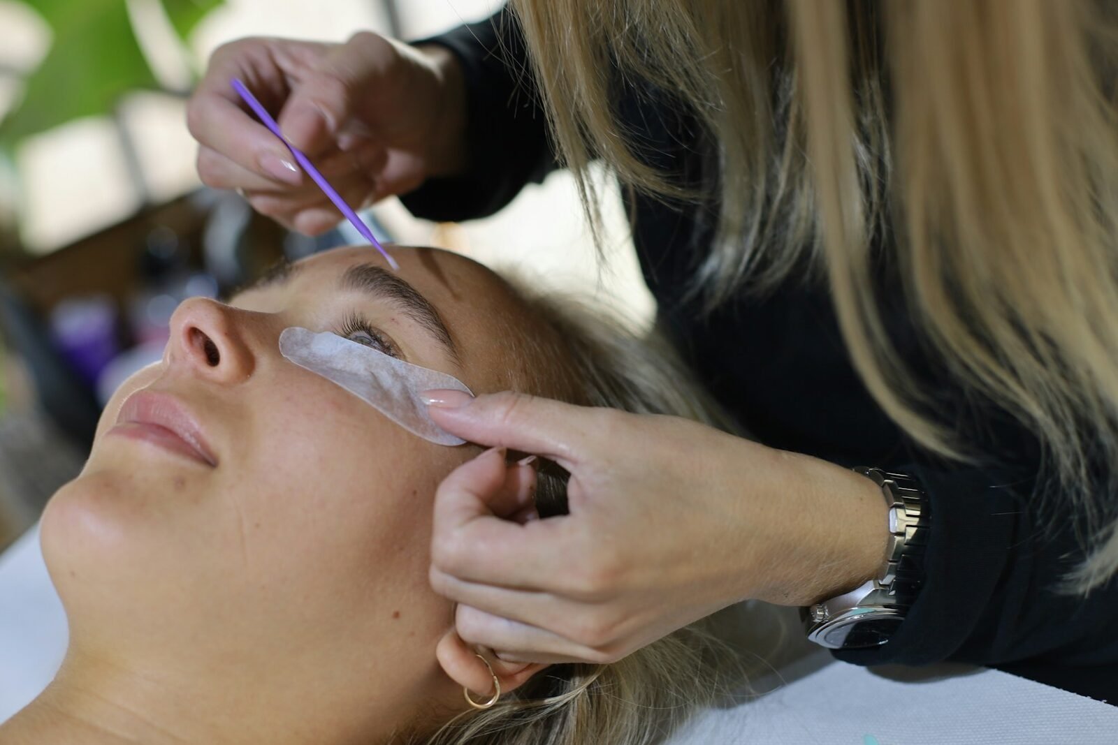Lash designer aplicando cílios fio a fio com pinça em cliente