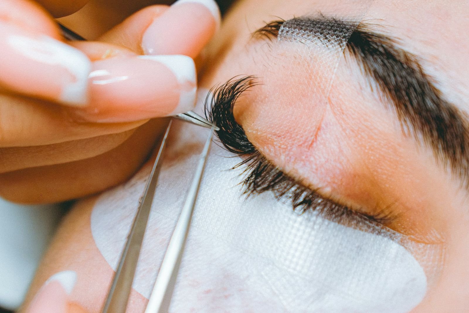 Profissional aplicando extensão de cílios com pinça, o que é lash designer na prática