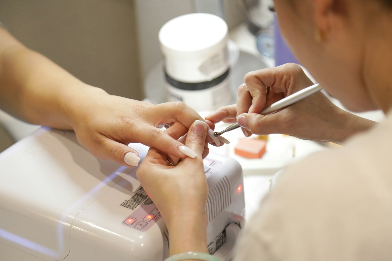 Manicure trabalhando as unhas de uma cliente em salão, um dos tipos de alongamento de unhas
