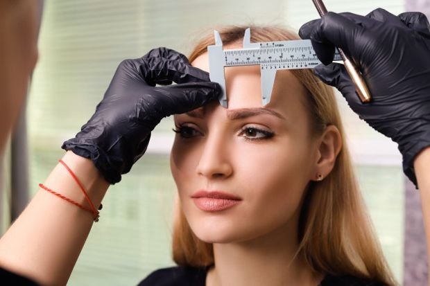 Esteticista medindo sobrancelha com paquimetro para mapeamento facial