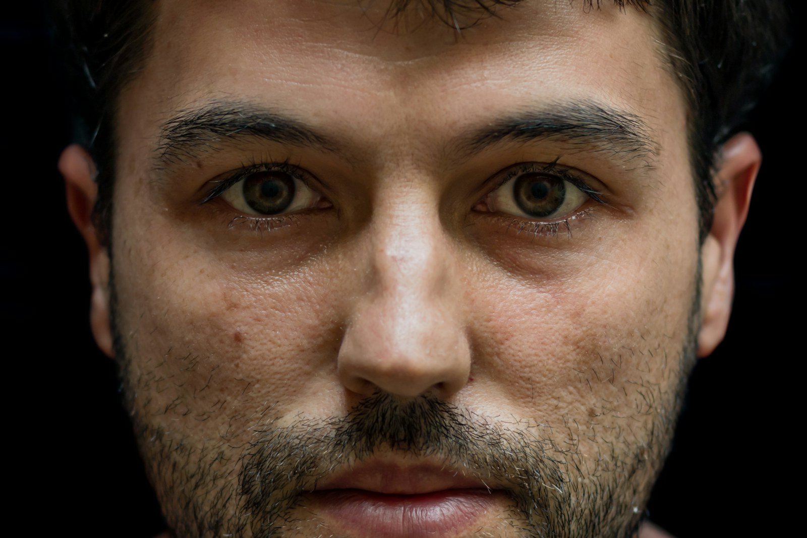 Sobrancelha masculina feita com acabamento natural: retrato frontal de um homem com barba e sobrancelhas grossas