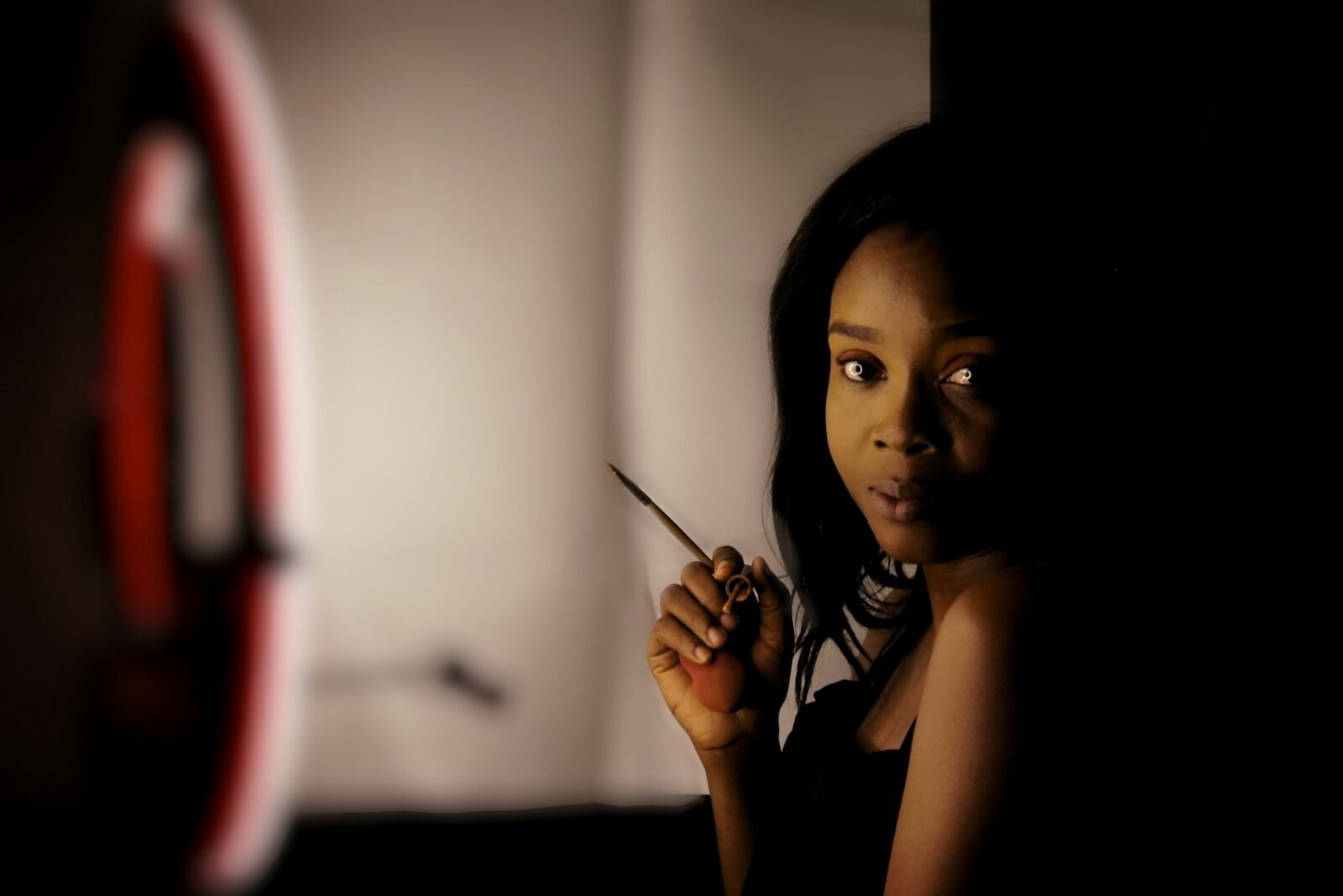 mulher de pele negra com pincel de maquiagem na mão, se arrumando para sair à noite