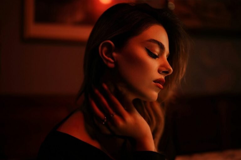 mulher com maquiagem simples para noite, delineado fino e batom vermelho, em luz baixa e quente
