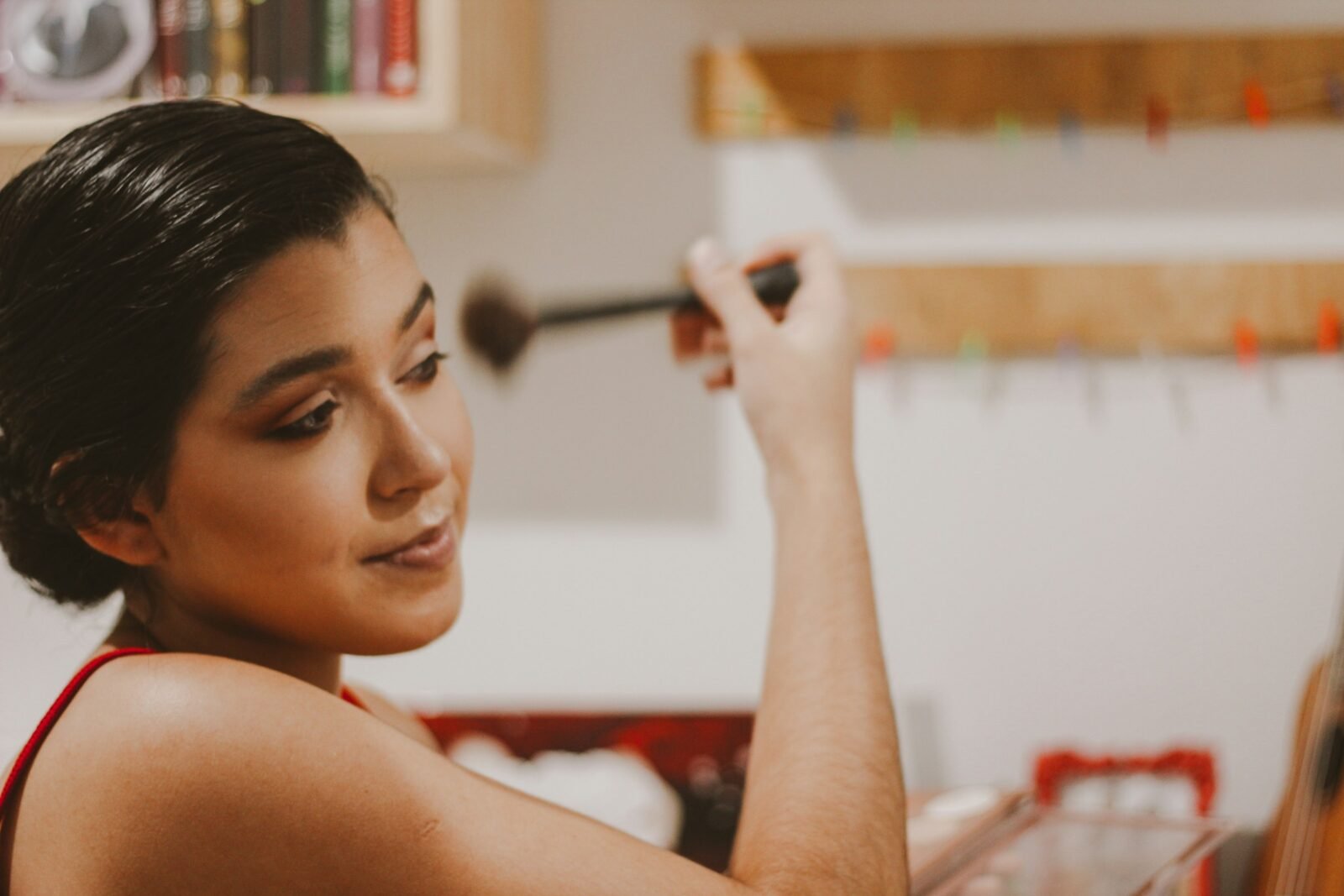 pincéis de maquiagem e suas funções: mulher usando pincel diante do espelho